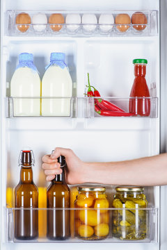 cropped image of man taking bottle of beer from fridge