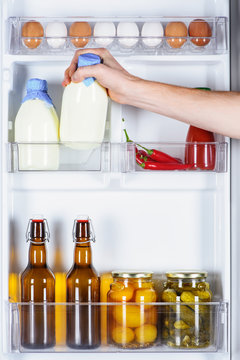 cropped image of man taking bottle of milk from fridge