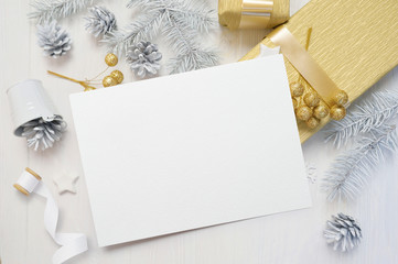 abstract christmas background, white sheet of paper lying among small decorations on white wooden desk. Flat lay mockup for your art, picture or hand lettering composition copy space, top view