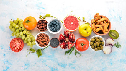 Healthy food on a white wooden table. Fresh vegetables, fruits, nuts, berries, mushrooms. Top view. Free space for text.