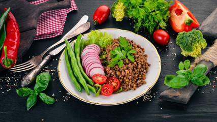 Lentil with radish, cherry tomatoes, beans and vegetables. Healthy food. On a black wooden table. Top view. Free space for text.
