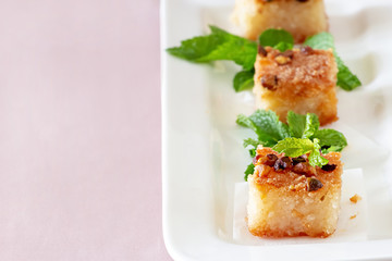 Three piecies Basbousa or Namoora traditional arabic dessert. Delicious homemade semolina cake with nuts on white plate.