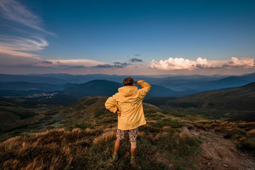 Fototapeta premium A young guy in a yellow raincoat on top of a mountain. Carpathians, Ukraine