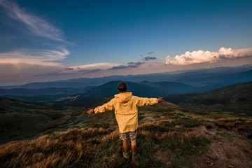 Fototapeta premium A young guy in a yellow raincoat on top of a mountain. Carpathians, Ukraine