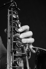 Man's hands with saxophone on dark background