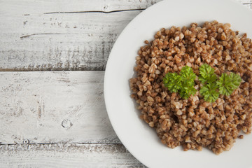 Cooked buckwheat on white wooden background. Healthy food. Copy space.