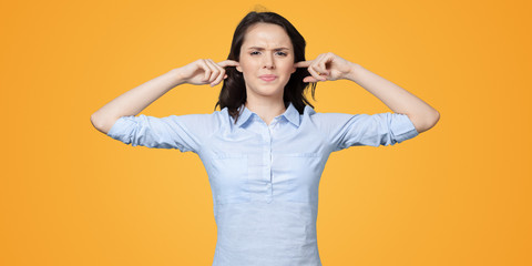 long-haired beautiful young brunette woman covering her ears with her hands