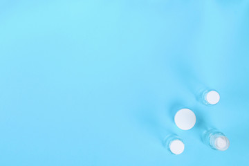 Set of empty small traveling cosmetics bottles on blue background. For soap, shampoo, shower gel, spray. Top view. Flat lay. Copy space.