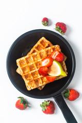 Food concept square Waffles and syrup with strawberry and fig topping in iron pan with copy space
