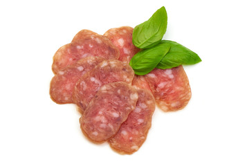 Smoked sausage thin slices and green basil leaves, isolated on white background