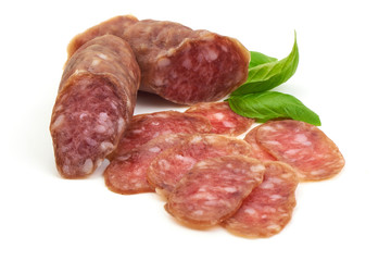 Smoked sausage with thin slices and green basil leaves, isolated on white background