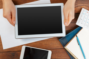 woman holding blank tablet device over a wooden workspace table