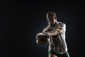 Isolated dirty rugby player with rugby ball on dark background