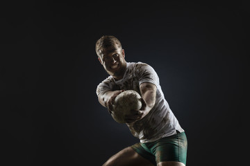 Isolated dirty rugby player with rugby ball on dark background