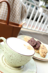 A cup of latte coffee and a cookie in a summer cafe on the table