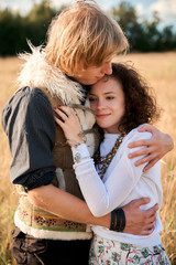 Boho style attractive couple in love posing on the autumn field. Family having fun and laughing. Gypsy style clothes. Young blonde man and beautiful caucasian woman together outdoor.