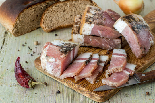    Pieces of salted lard with pepper and black rye bread on an old wooden table. 