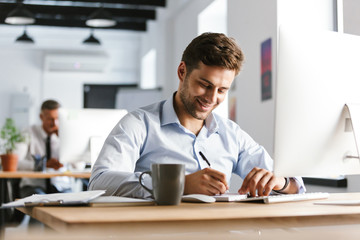 Image of Smiling male manager writing something