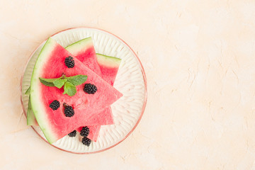 Watermelon slice pie with blackberries and mint leaf on pastel yellow background with copy space.