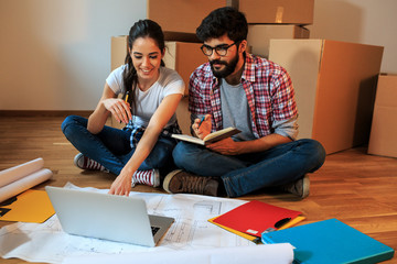Young couple moving into a new house.They sitting on floor and calculate savings and home budget.