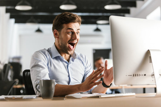 Shocked screaming business man using computer while sitting by table