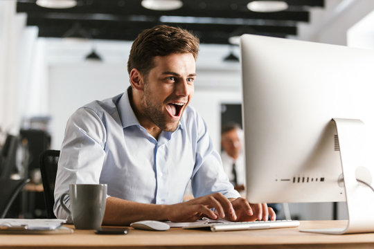 Cheerful screaming business man using computer and rejoices