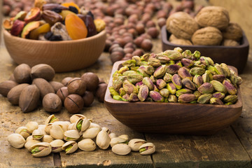 pistachios nuts peeled in wooden bowl on table, grunge style.