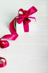 Gift birthday Christmas present concept - white gift box with red ribbon on white painted wooden background
