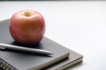 Red apple with pen on the books and white background