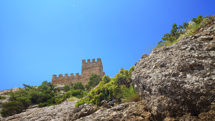 Fototapeta na wymiar Genoese fortress view from below, the bright daytime photo fortress on a background of blue sky