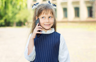 Call your parents. Girl schoolgirl talking on mobile phone in front of school.