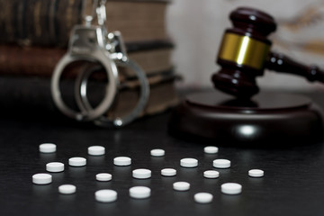 Judge's gavel with handcuffs, drugs on wooden table