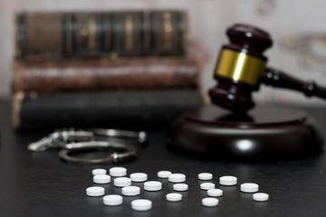 Judge's gavel with handcuffs, drugs on wooden table
