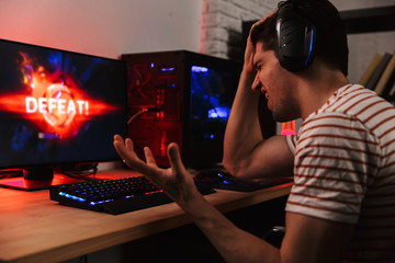 Side view of confused gamer playing video games on computer
