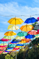 Fototapeta na wymiar Different colorful umbrellas hanging over the street against sky