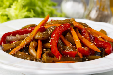 Vegetable salad. Aubergines fried, pepper, carrots on a white plate. The concept of healthy eating. White wooden background. Copy space