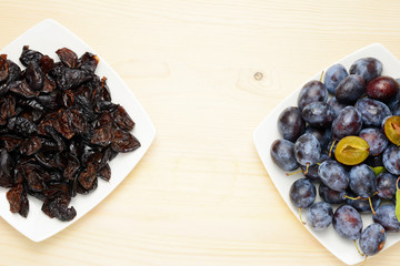 Fresh and dried plums with leaves on a wooden table background, Flat lay composition.