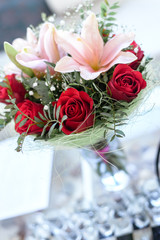 Fresh bouquet of red roses, lily with a party mask.