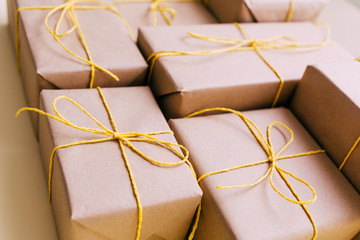 Gift boxes wrapped in brown kraft paper and tied with twine with beads lie on a yellow background. Gift delivery.Close-up.Design postcards for the holidays. Place for text