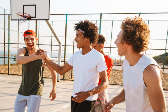 Image of young men basketball players standing at the playground outdoor, during summer sunny day