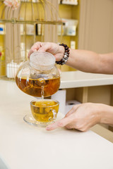 women's hands pour green tea in a spa