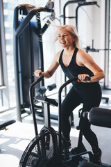 Young woman riding on an air bike at the gym.