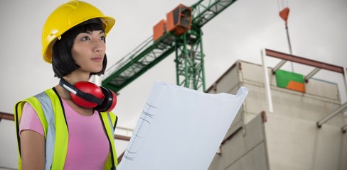 Composite image of female architect holding blueprint against