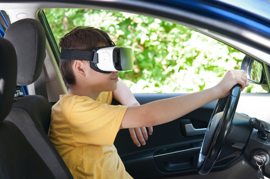 A teenager in a virtual reality helmet driving a car.