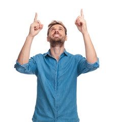 smiling casual man pointing fingers above his head