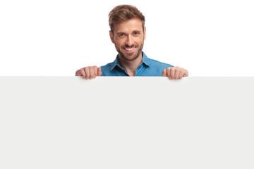 smiling young casual man presenting a blank board
