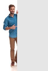 happy casual man poiting finger at a blank board