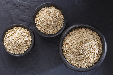 Quinoa grains with spoon and bowl on black background