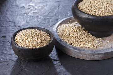Quinoa grains with spoon and bowl on black background