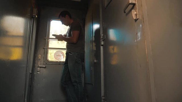 the man silhouette is standing on the train Railway carriage holding a smartphone and . slow motion video. man writes messages in the smartphone in the train social media lifestyle. man with